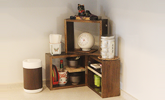 L字型キッチンのコーナーには自作の棚と自作の小物を配置して使いやすく。既製品のウェットティッシュケースにも木目シートを貼る徹底ぶり。